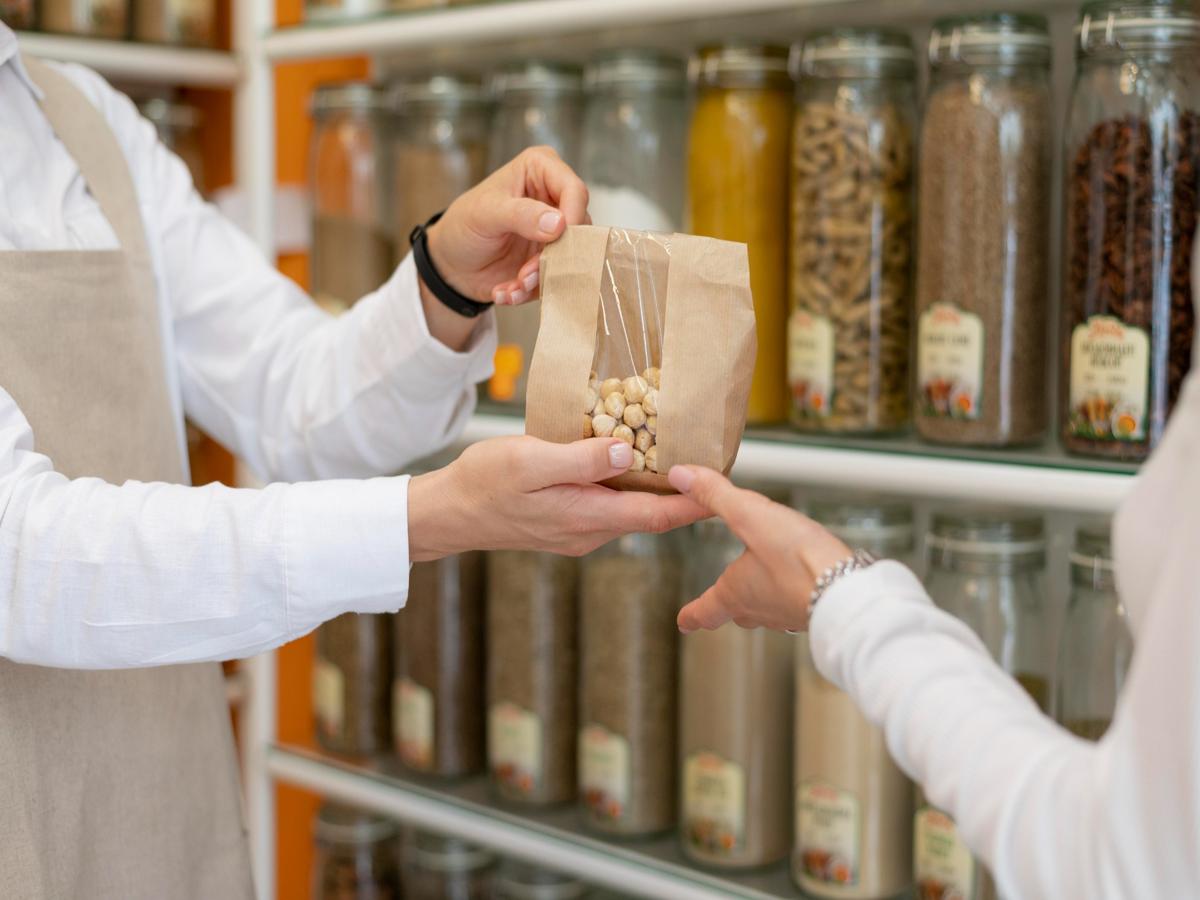 Imagen que muestra a un cliente recibiendo un paquete con frutos secos en una tienda especializada, destacando la importancia de un buen diseño web para empresa de alimentación en Barcelona.